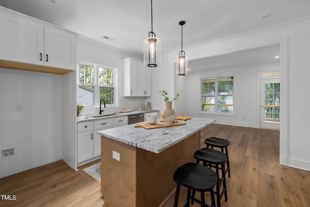 kitchen featuring sink, white cabinetry, decorative light fixtures, stainless steel dishwasher, and light stone countertops