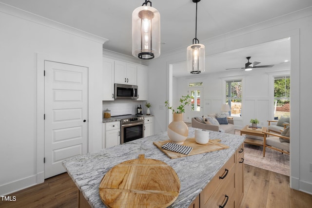 kitchen featuring white cabinetry, stainless steel appliances, light stone countertops, and a kitchen island