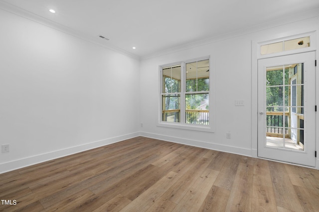 empty room with a healthy amount of sunlight, ornamental molding, and light hardwood / wood-style flooring