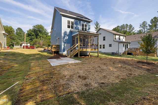 rear view of house featuring a wooden deck, a lawn, and a sunroom