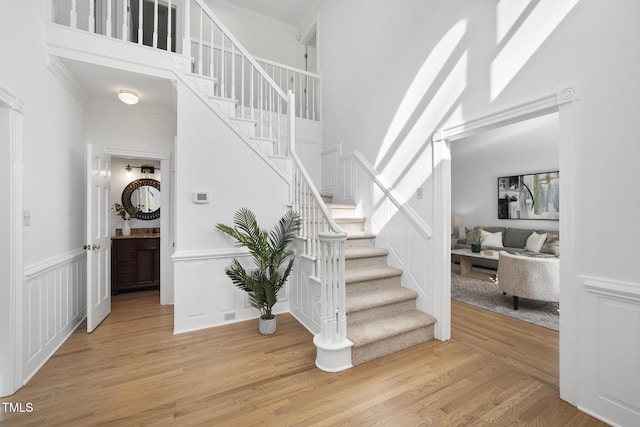 stairway with hardwood / wood-style floors, crown molding, and a towering ceiling