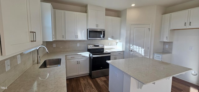 kitchen with sink, backsplash, stainless steel appliances, white cabinets, and a kitchen island