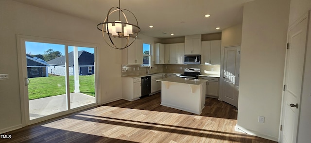 kitchen featuring an inviting chandelier, a kitchen island, white cabinets, and appliances with stainless steel finishes