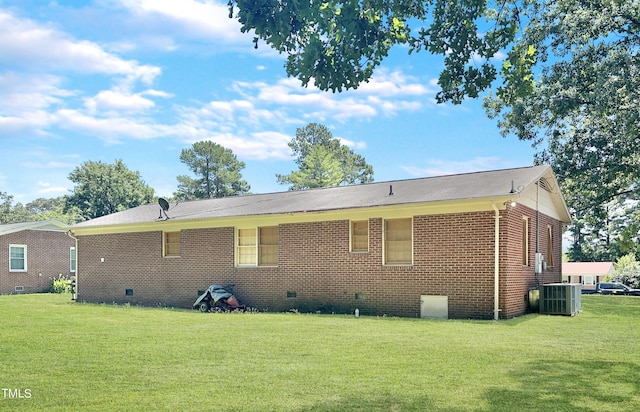 back of house with central AC unit and a lawn