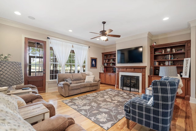 living room featuring hardwood / wood-style flooring, ceiling fan, and crown molding