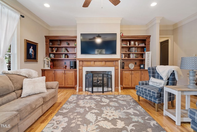 living room with crown molding, ceiling fan, and light wood-type flooring