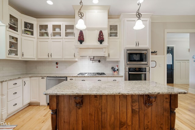 kitchen with light stone counters, hanging light fixtures, decorative backsplash, and stainless steel appliances