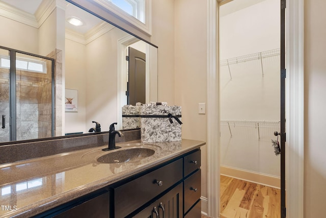 bathroom with a shower with door, wood-type flooring, a wealth of natural light, and vanity