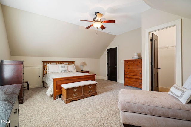 bedroom featuring lofted ceiling, ceiling fan, carpet flooring, a walk in closet, and a closet