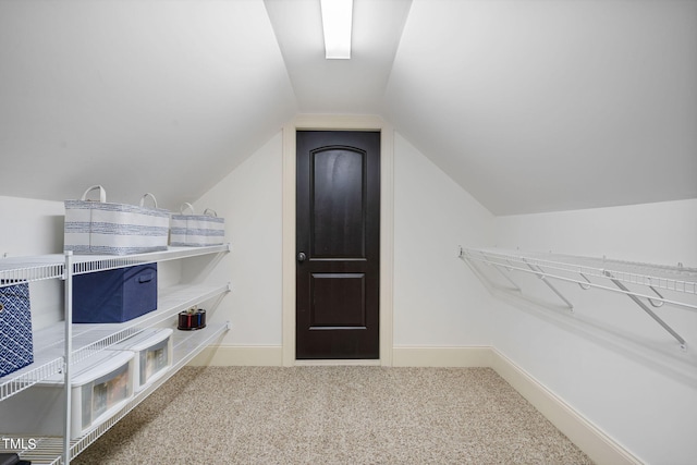 walk in closet with vaulted ceiling and carpet flooring