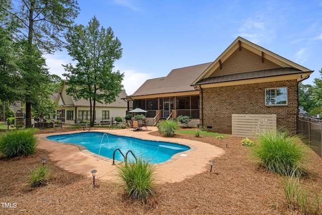 view of pool with pool water feature, a patio area, and a sunroom