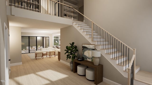 stairway featuring baseboards, a high ceiling, and wood finished floors