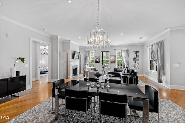 dining area featuring light wood-type flooring, a fireplace, baseboards, a notable chandelier, and recessed lighting