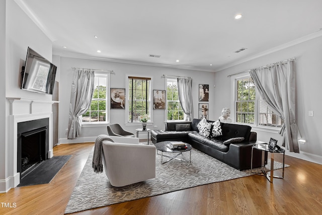 living area with a fireplace with flush hearth, wood finished floors, visible vents, and ornamental molding