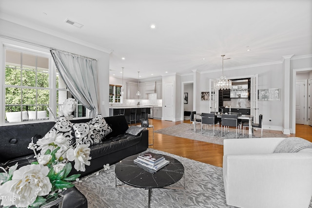 living area with recessed lighting, light wood finished floors, visible vents, crown molding, and a notable chandelier