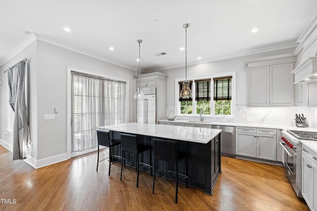 kitchen with high end appliances, a center island, light hardwood / wood-style floors, and a breakfast bar