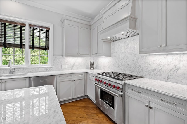 kitchen with white cabinets, stainless steel appliances, a sink, ornamental molding, and premium range hood