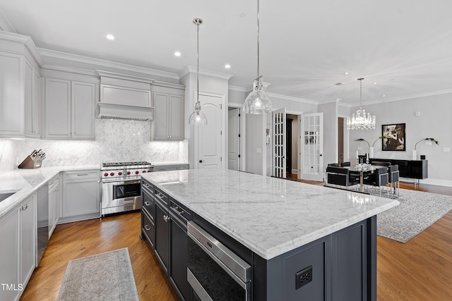 kitchen featuring a center island, backsplash, appliances with stainless steel finishes, light stone countertops, and recessed lighting