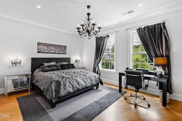 bedroom with a notable chandelier, wood-type flooring, and crown molding