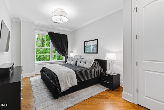 bedroom with light wood-type flooring, baseboards, ornamental molding, and visible vents
