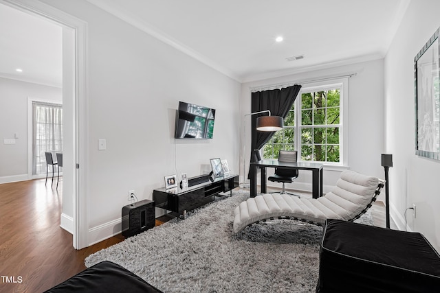 living area with baseboards, crown molding, wood finished floors, and visible vents