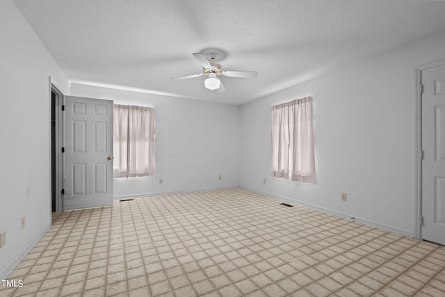 empty room with ceiling fan and a textured ceiling