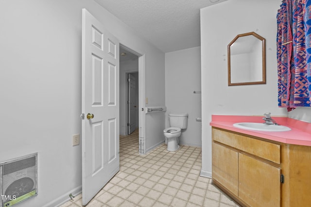 bathroom featuring vanity, a textured ceiling, heating unit, and toilet