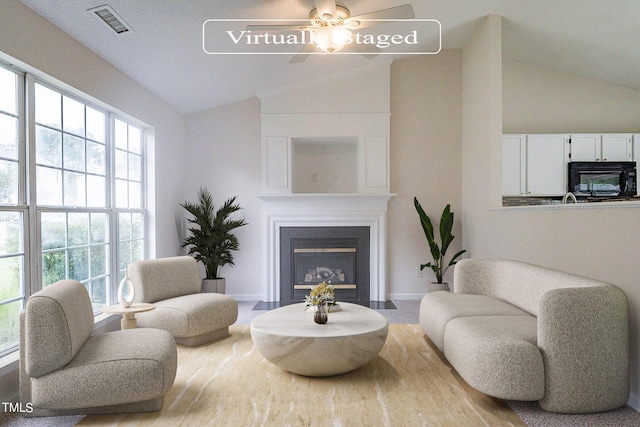 living area with ceiling fan and lofted ceiling