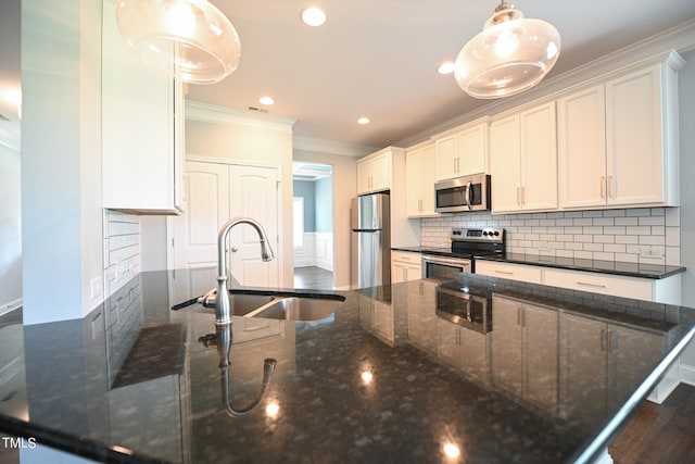 kitchen with dark stone countertops, dark hardwood / wood-style flooring, appliances with stainless steel finishes, pendant lighting, and sink