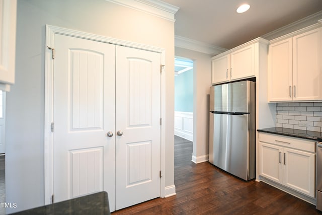 kitchen with tasteful backsplash, white cabinets, stainless steel refrigerator, crown molding, and dark hardwood / wood-style floors