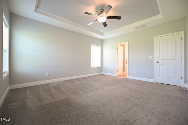 carpeted spare room featuring ceiling fan and a tray ceiling