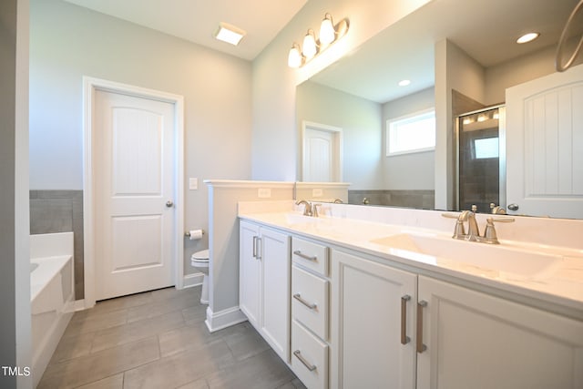 bathroom with a washtub, tile patterned floors, toilet, and dual bowl vanity