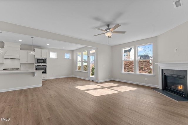 unfurnished living room featuring ceiling fan and light hardwood / wood-style flooring