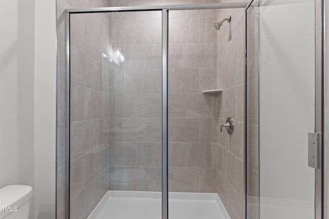 bathroom with a shower with shower door and toilet