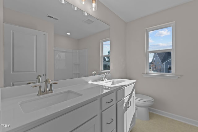 bathroom with tile patterned floors, vanity, a healthy amount of sunlight, and toilet