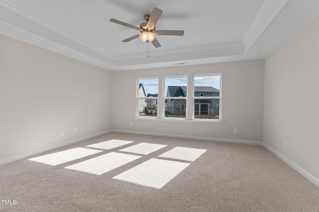 carpeted spare room with a raised ceiling, ceiling fan, and crown molding