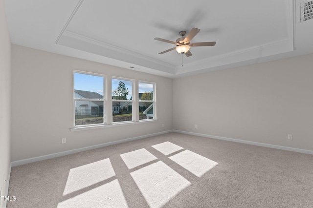 carpeted empty room with a raised ceiling, ceiling fan, and crown molding