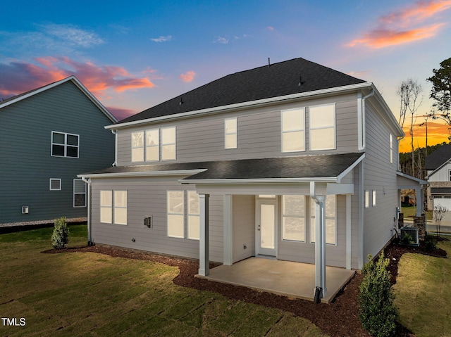 back house at dusk featuring a patio, central AC, and a lawn