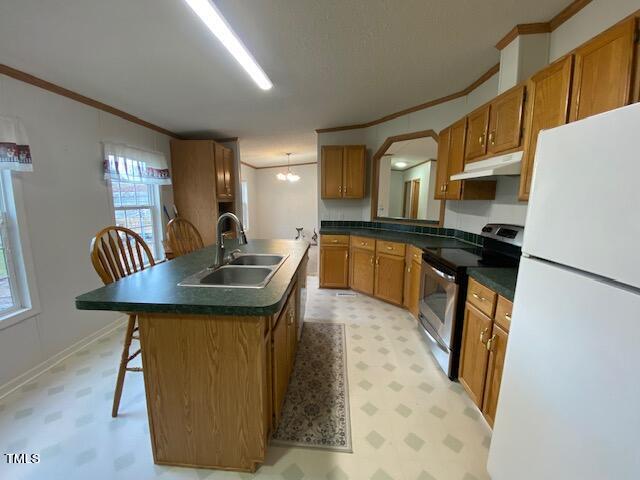 kitchen featuring ornamental molding, a kitchen island with sink, a kitchen breakfast bar, stainless steel range with electric cooktop, and white fridge