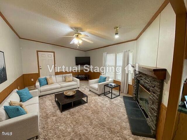 carpeted living room featuring ornamental molding, a textured ceiling, a fireplace, and ceiling fan