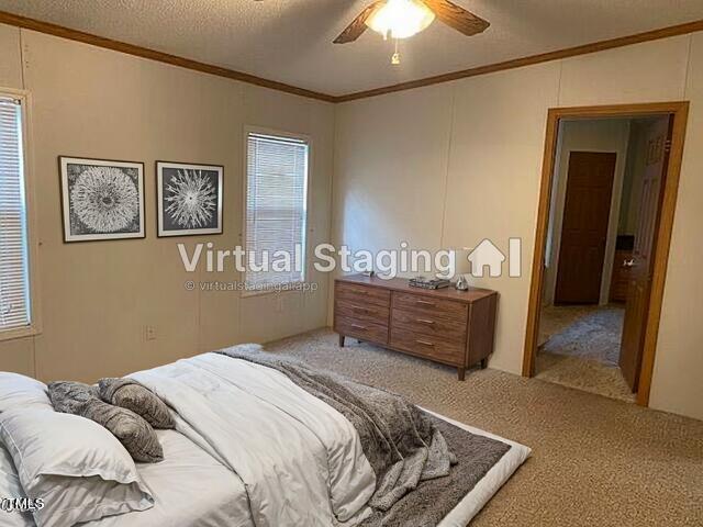 bedroom with carpet flooring, ornamental molding, a textured ceiling, and ceiling fan