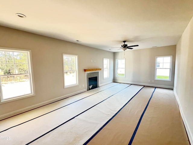 unfurnished living room featuring ceiling fan and a tiled fireplace