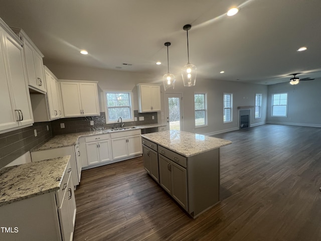 kitchen featuring sink, decorative light fixtures, white cabinets, and a kitchen island