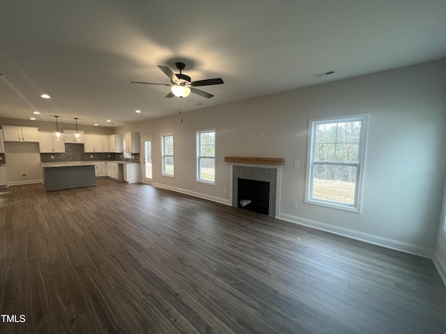 unfurnished living room with dark wood-type flooring, ceiling fan, and a tile fireplace