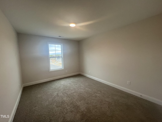 spare room with dark carpet