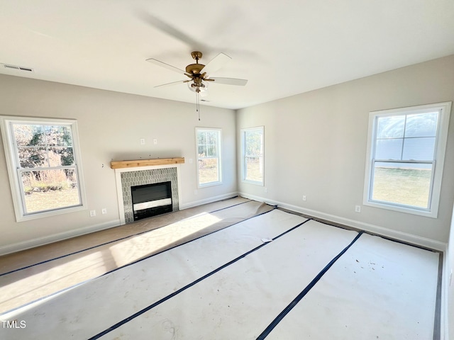 unfurnished living room featuring ceiling fan and a tiled fireplace