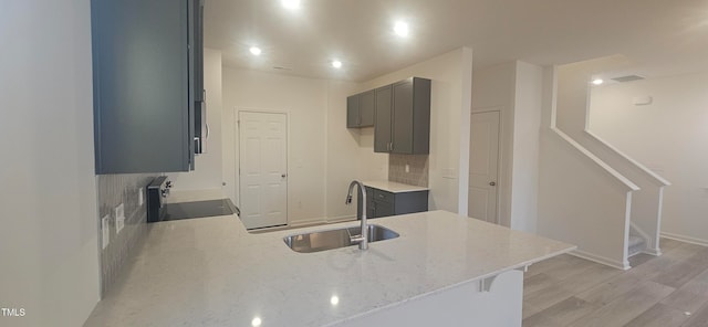 kitchen featuring range, sink, light hardwood / wood-style flooring, gray cabinets, and kitchen peninsula