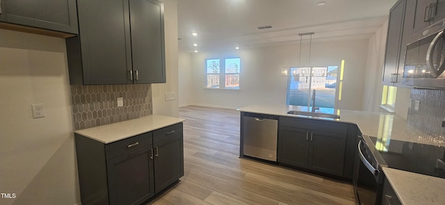 kitchen with decorative backsplash, dishwasher, a peninsula, light wood-type flooring, and a sink