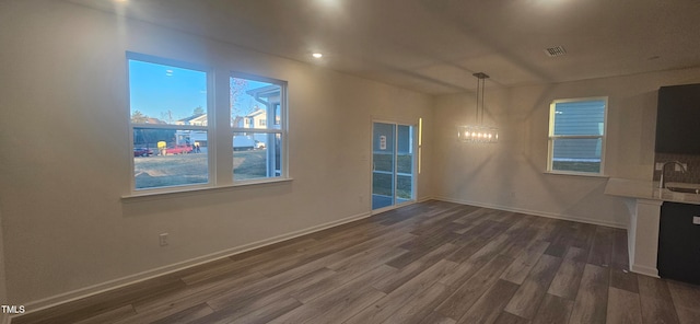 unfurnished dining area with a sink, dark wood finished floors, visible vents, and baseboards