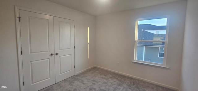 unfurnished bedroom with carpet floors, baseboards, and a closet